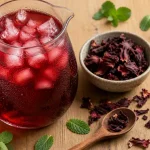 Boisson hibiscus rubis en pichet, glaçons et fleurs d’hibiscus